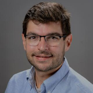 Smiling Caucasian man wearing glasses and a blue button up