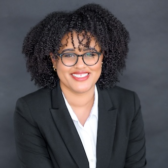 Smiling woman wearing glasses, a black blazer and a white button up