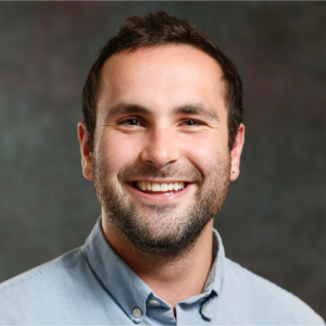 Smiling man with short brown hair wearing a blue button up