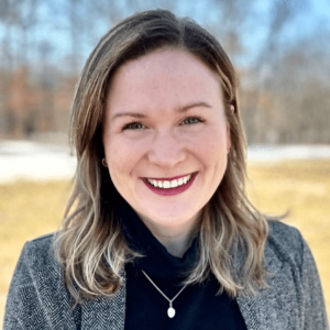 Smiling Caucasian woman with a gray blazer and black turtleneck