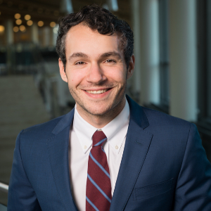 Smiling man wearing a navy blazer with a burgundy and blue tie