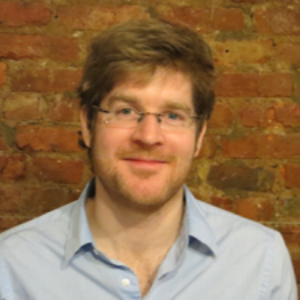 Smiling man with glasses wearing a light blue button up shirt