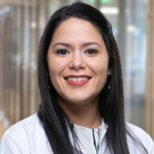 Smiling woman wearing a white blouse and medical lab coat