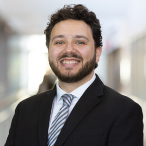 Smiling man wearing a black blazer and blue striped tie