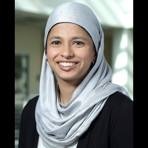 Smiling woman wearing a light blue hijab and dark blue blouse