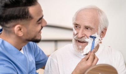 Nurse shaving the face of an elderly patient