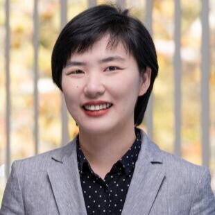 Smiling Asian woman wearing a gray blazer and a black and white button up