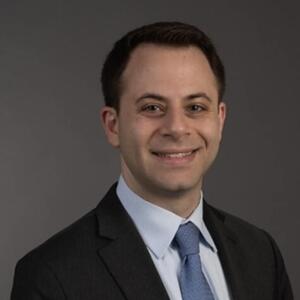 Smiling man wearing a black blazer with a blue tie