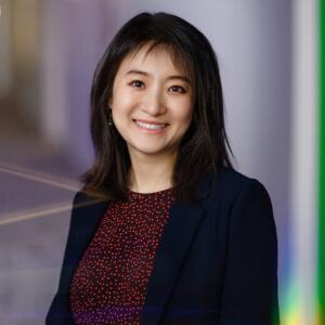 Smiling woman wearing a navy blazer and red polka dot blouse