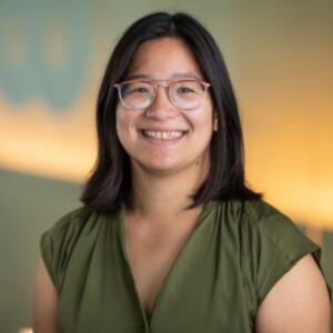 Smiling Asian woman wearing glasses and an olive green shirt