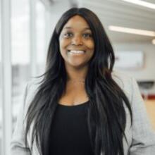 Smiling Black woman with a gray blazer and black blouse